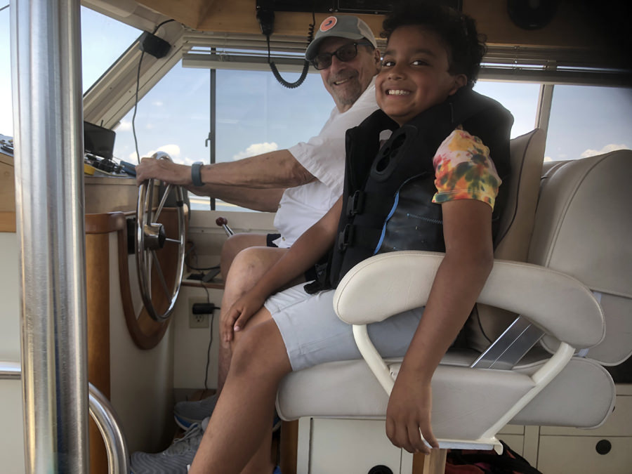 Young boy sitting next to the captain on a boat.