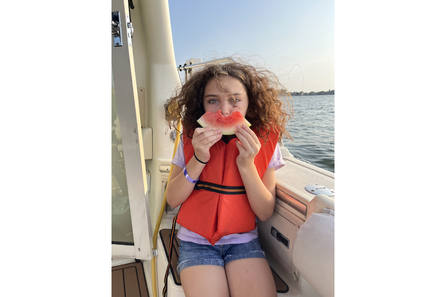 Young girl sitting on a boat eating watermelon