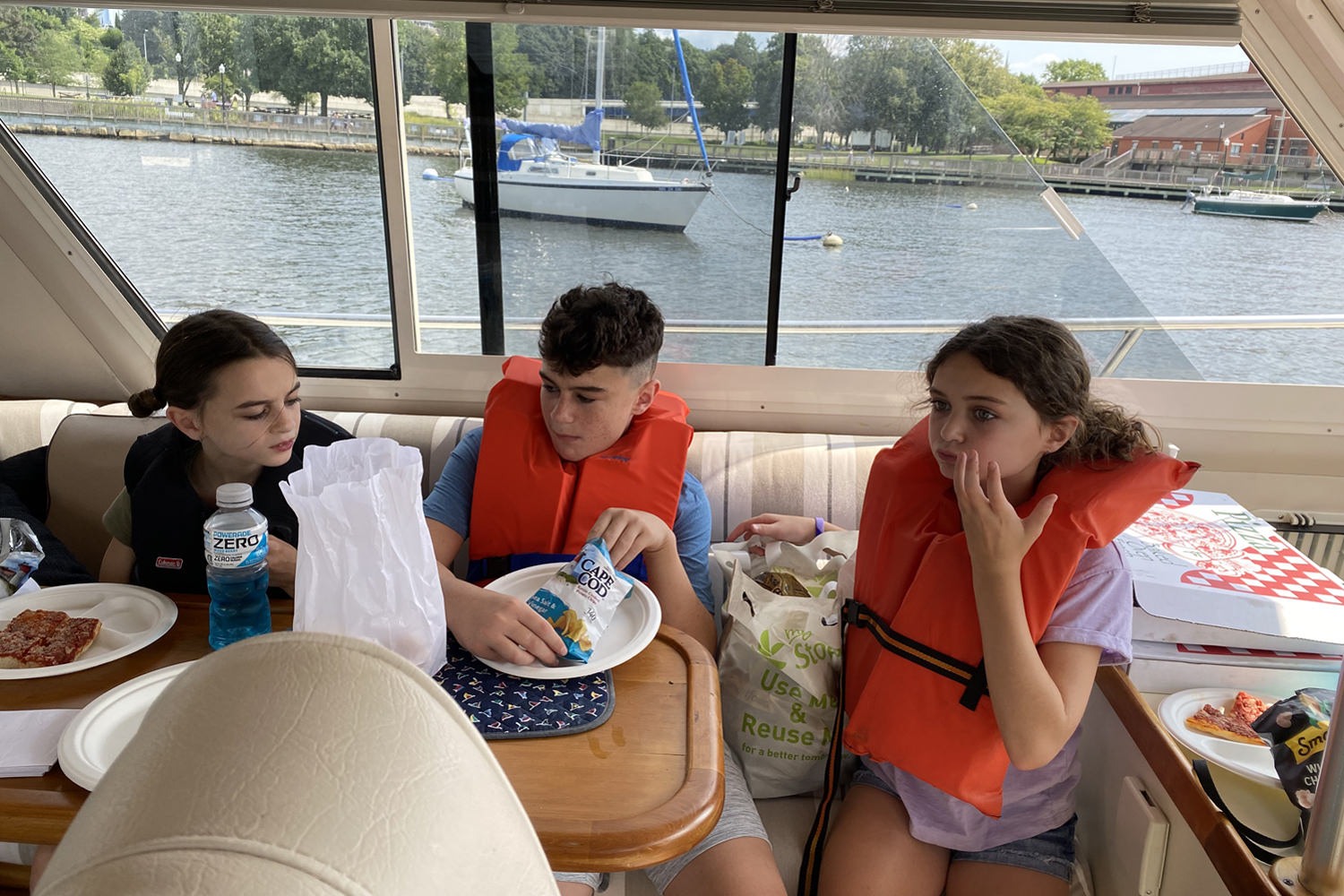 Three children sitting around a table eating on a boat