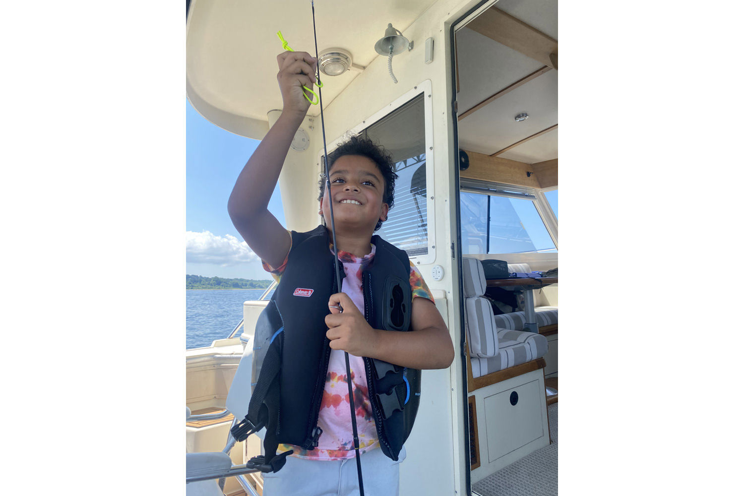 Young boy standing on a boat holding a fishing  poll